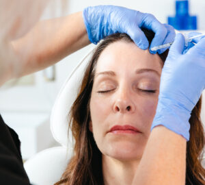 A patient shuts her eyes while a provider wearing gloves administers an injection of Botox in Brentwood, TN.